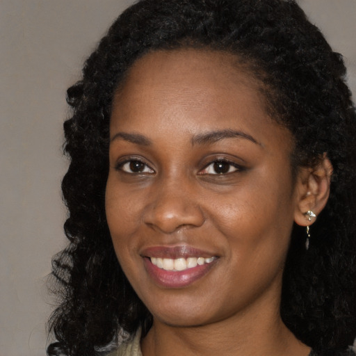 Joyful black young-adult female with long  brown hair and brown eyes