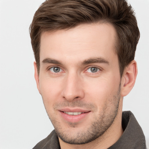 Joyful white young-adult male with short  brown hair and grey eyes