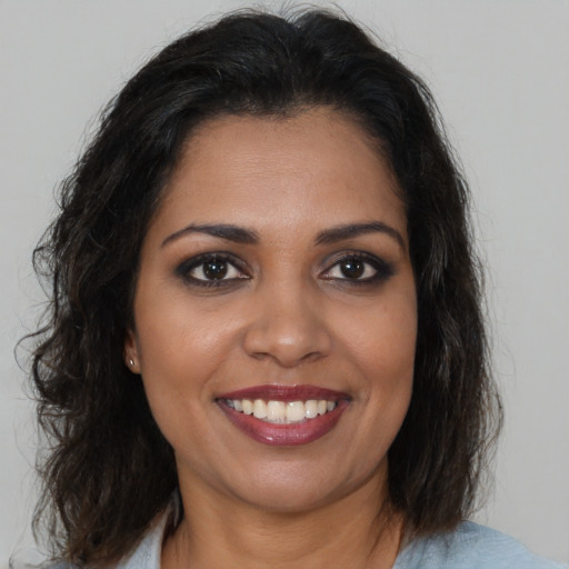 Joyful black young-adult female with long  brown hair and brown eyes