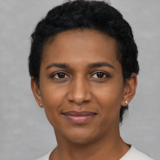 Joyful black young-adult female with short  black hair and brown eyes
