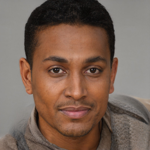 Joyful black young-adult male with short  brown hair and brown eyes