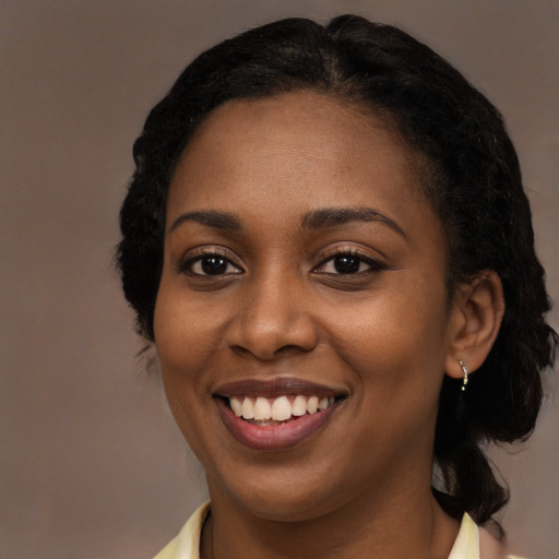 Joyful black young-adult female with long  black hair and brown eyes