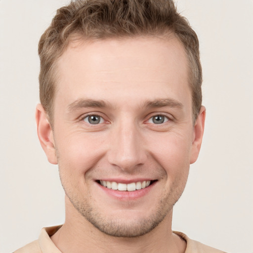 Joyful white young-adult male with short  brown hair and grey eyes