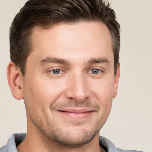 Joyful white young-adult male with short  brown hair and grey eyes