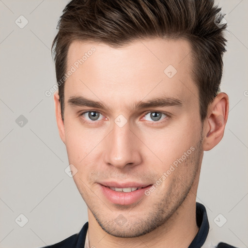 Joyful white young-adult male with short  brown hair and grey eyes