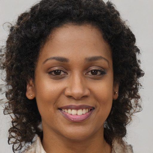 Joyful black young-adult female with long  brown hair and brown eyes