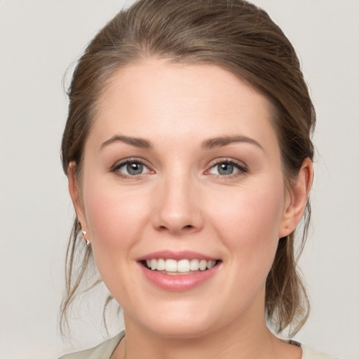 Joyful white young-adult female with medium  brown hair and grey eyes