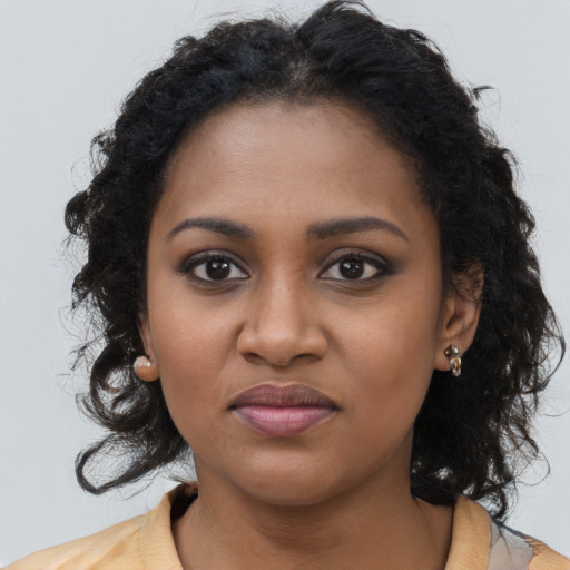 Joyful black young-adult female with long  brown hair and brown eyes