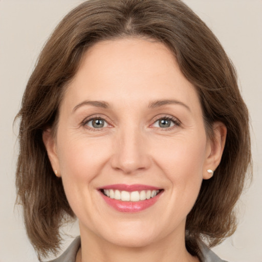 Joyful white adult female with medium  brown hair and grey eyes