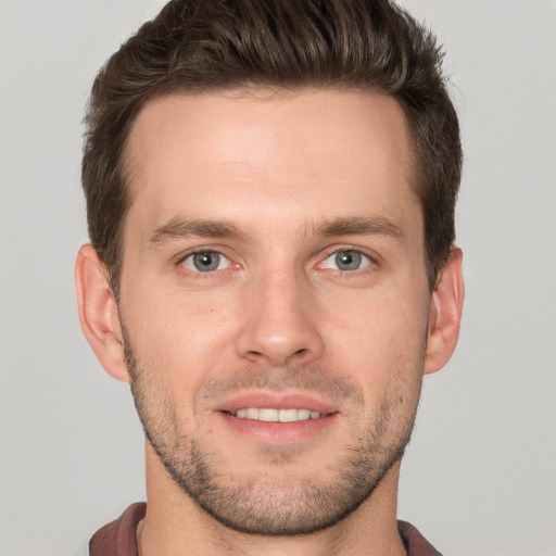 Joyful white young-adult male with short  brown hair and grey eyes