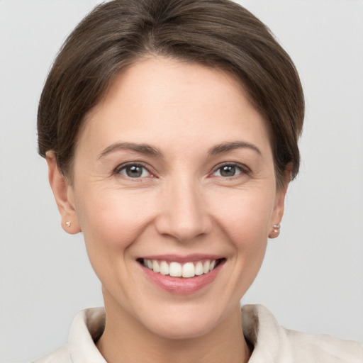 Joyful white young-adult female with short  brown hair and grey eyes