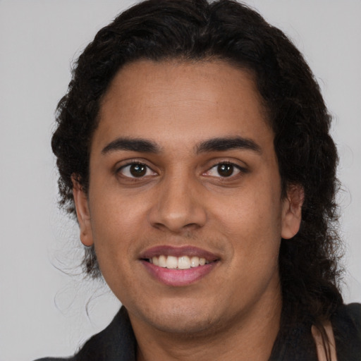 Joyful latino young-adult male with long  brown hair and brown eyes