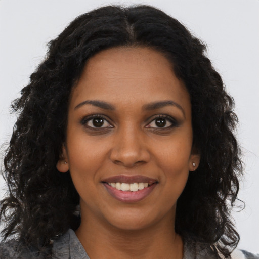 Joyful black young-adult female with long  brown hair and brown eyes