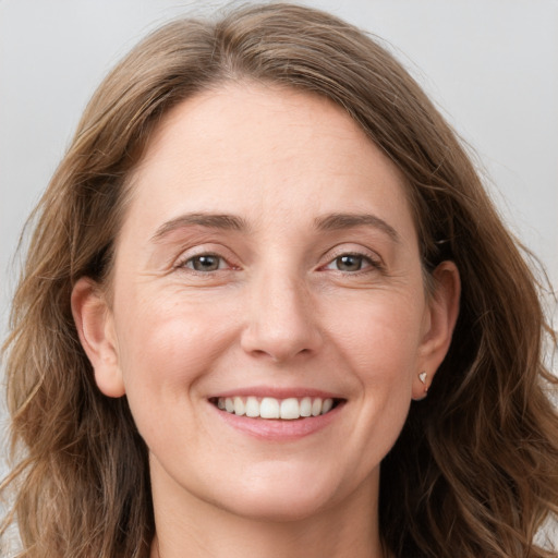 Joyful white adult female with long  brown hair and grey eyes