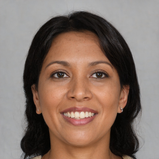 Joyful latino adult female with medium  black hair and brown eyes