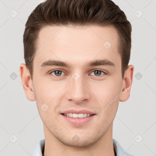 Joyful white young-adult male with short  brown hair and grey eyes