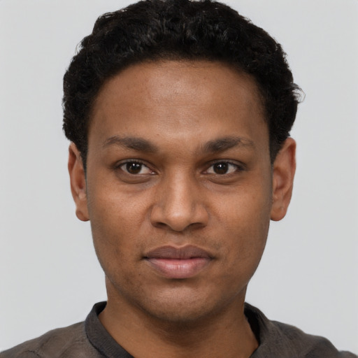 Joyful black young-adult male with short  black hair and brown eyes