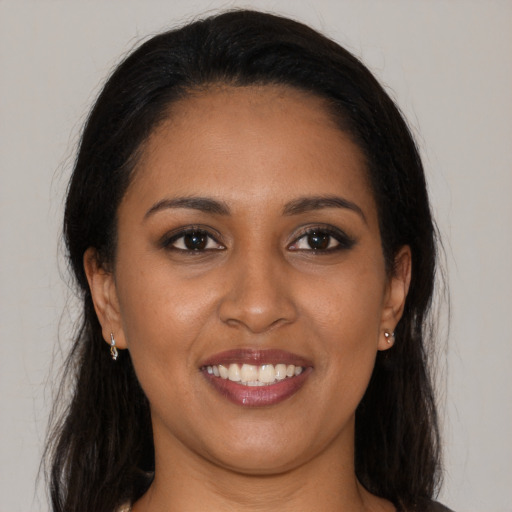 Joyful black young-adult female with long  brown hair and brown eyes