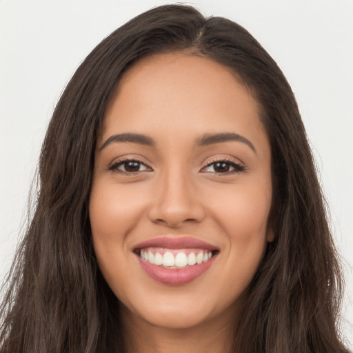 Joyful latino young-adult female with long  brown hair and brown eyes