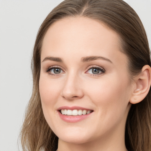 Joyful white young-adult female with long  brown hair and blue eyes