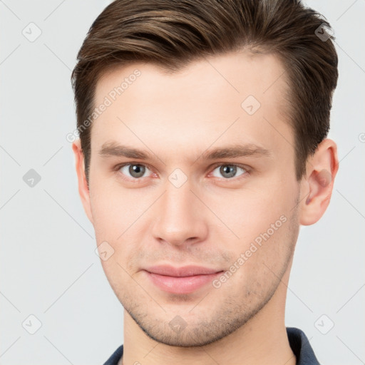 Joyful white young-adult male with short  brown hair and grey eyes