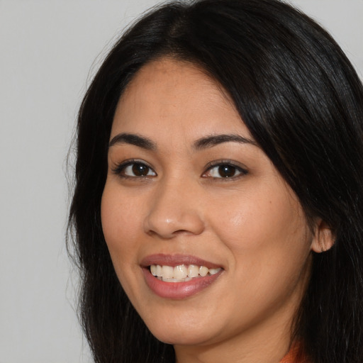 Joyful latino young-adult female with long  brown hair and brown eyes