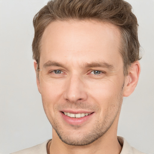 Joyful white young-adult male with short  brown hair and grey eyes