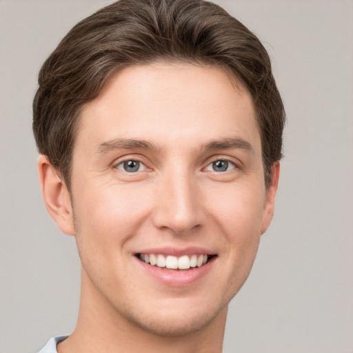 Joyful white young-adult male with short  brown hair and grey eyes