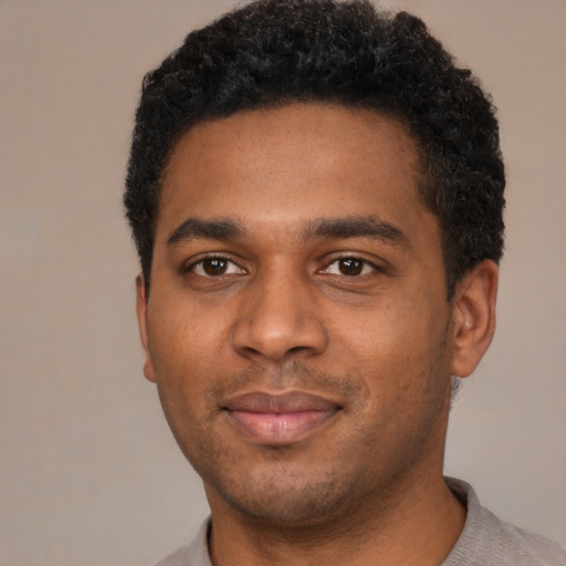 Joyful black young-adult male with short  black hair and brown eyes