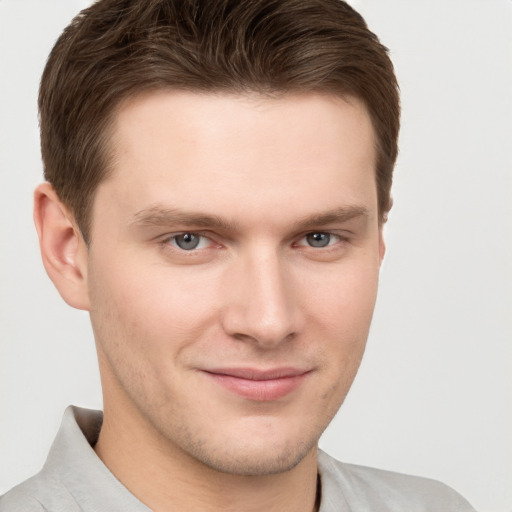 Joyful white young-adult male with short  brown hair and grey eyes