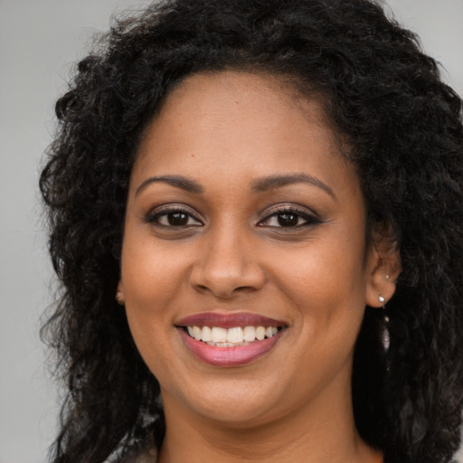 Joyful black young-adult female with long  brown hair and brown eyes