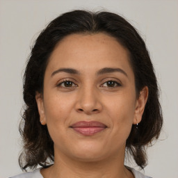 Joyful latino young-adult female with medium  brown hair and brown eyes