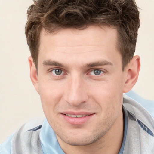 Joyful white young-adult male with short  brown hair and grey eyes