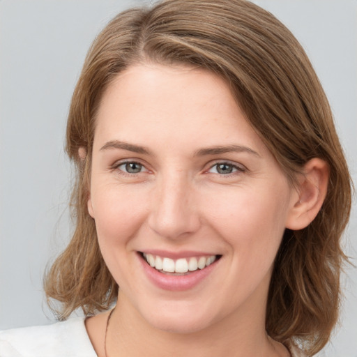 Joyful white young-adult female with medium  brown hair and grey eyes