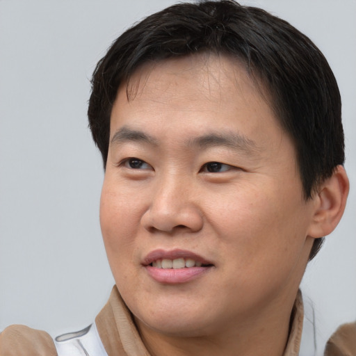 Joyful asian adult male with short  brown hair and brown eyes