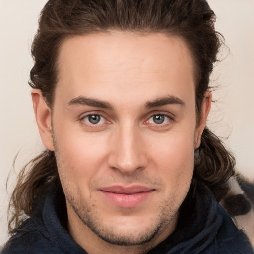 Joyful white young-adult male with long  brown hair and brown eyes