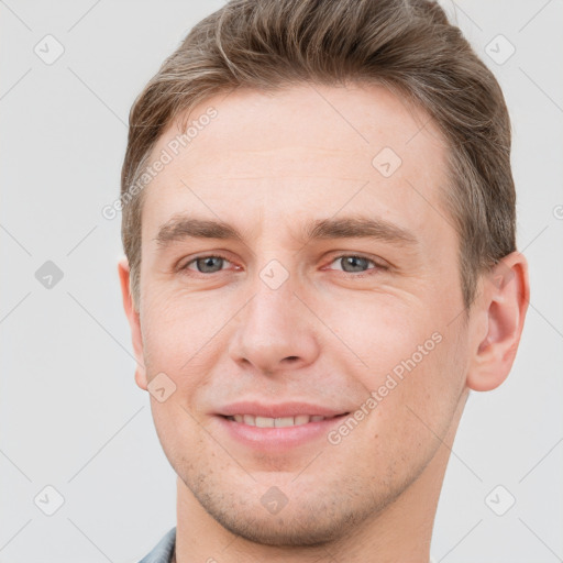 Joyful white young-adult male with short  brown hair and grey eyes