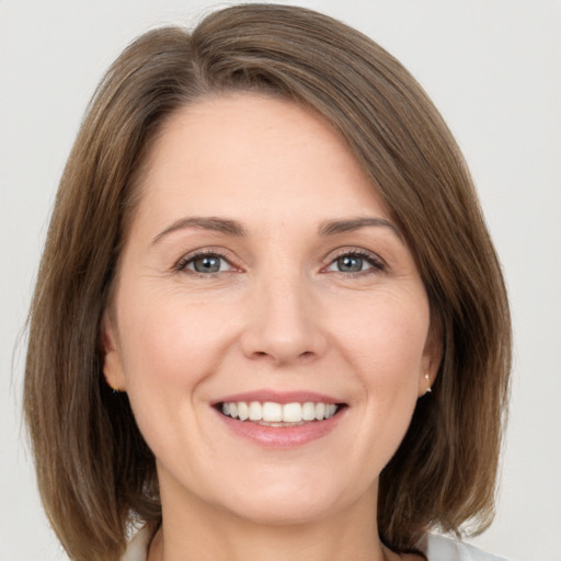 Joyful white young-adult female with medium  brown hair and grey eyes