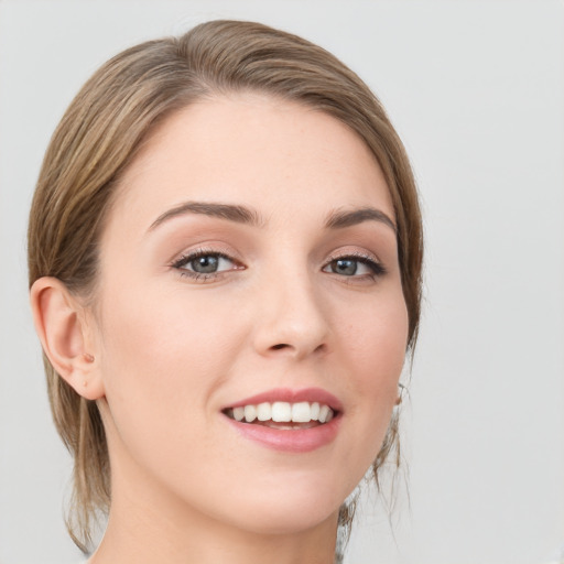 Joyful white young-adult female with medium  brown hair and grey eyes