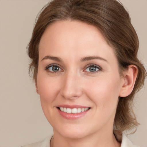 Joyful white young-adult female with medium  brown hair and grey eyes