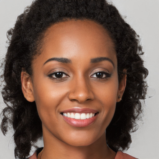 Joyful black young-adult female with long  brown hair and brown eyes