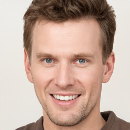 Joyful white young-adult male with short  brown hair and grey eyes