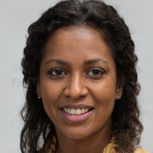 Joyful black young-adult female with long  brown hair and brown eyes