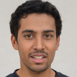 Joyful latino young-adult male with short  brown hair and brown eyes