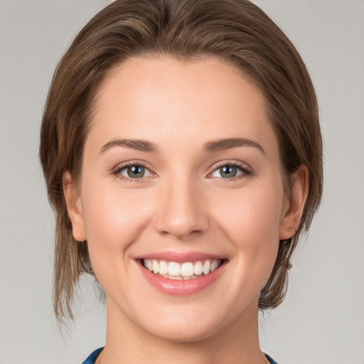 Joyful white young-adult female with medium  brown hair and grey eyes