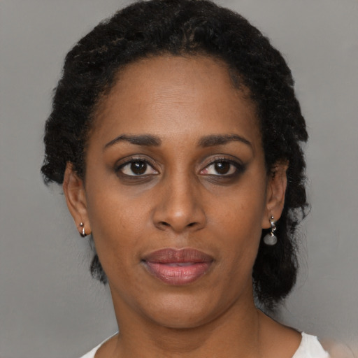 Joyful black young-adult female with short  black hair and brown eyes