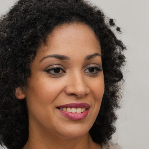 Joyful black young-adult female with long  brown hair and brown eyes