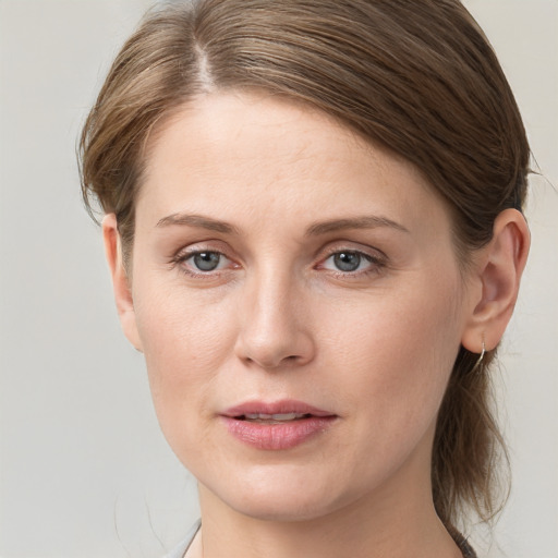 Joyful white young-adult female with medium  brown hair and grey eyes