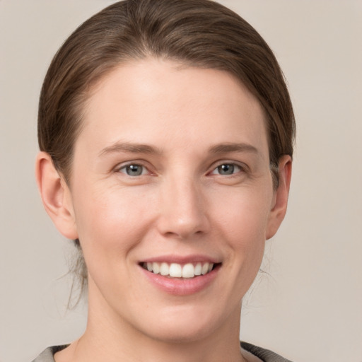 Joyful white young-adult female with medium  brown hair and grey eyes