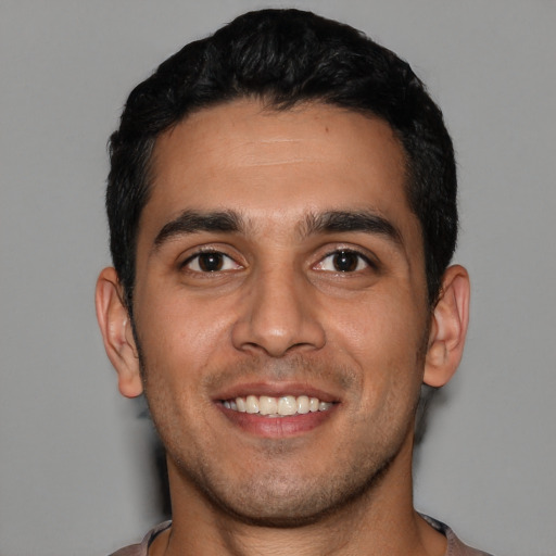 Joyful latino young-adult male with short  black hair and brown eyes